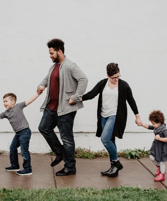 Family walking on sidewalk holding hands